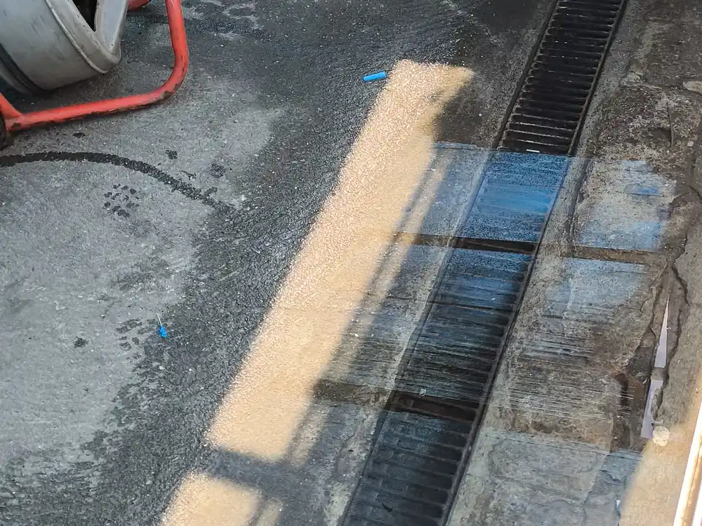 Canaleta de piso sendo desentupida com máquina em uma área externa