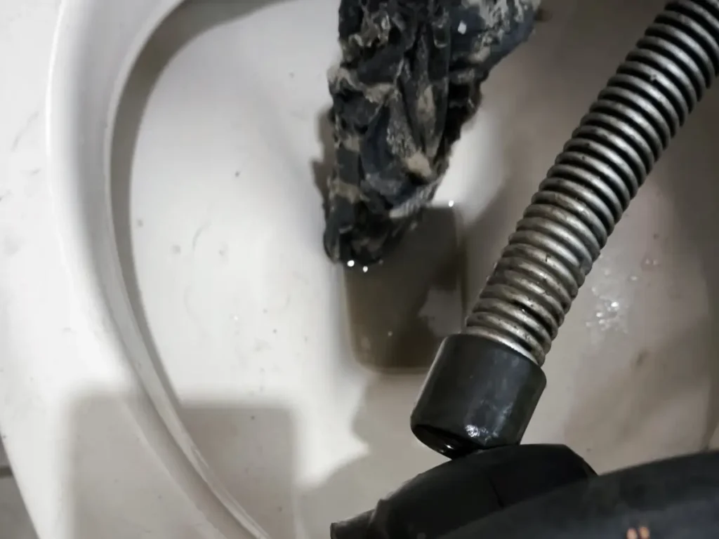 Máquina de desentupimento retirando pano e sujeira de dentro do vaso sanitário