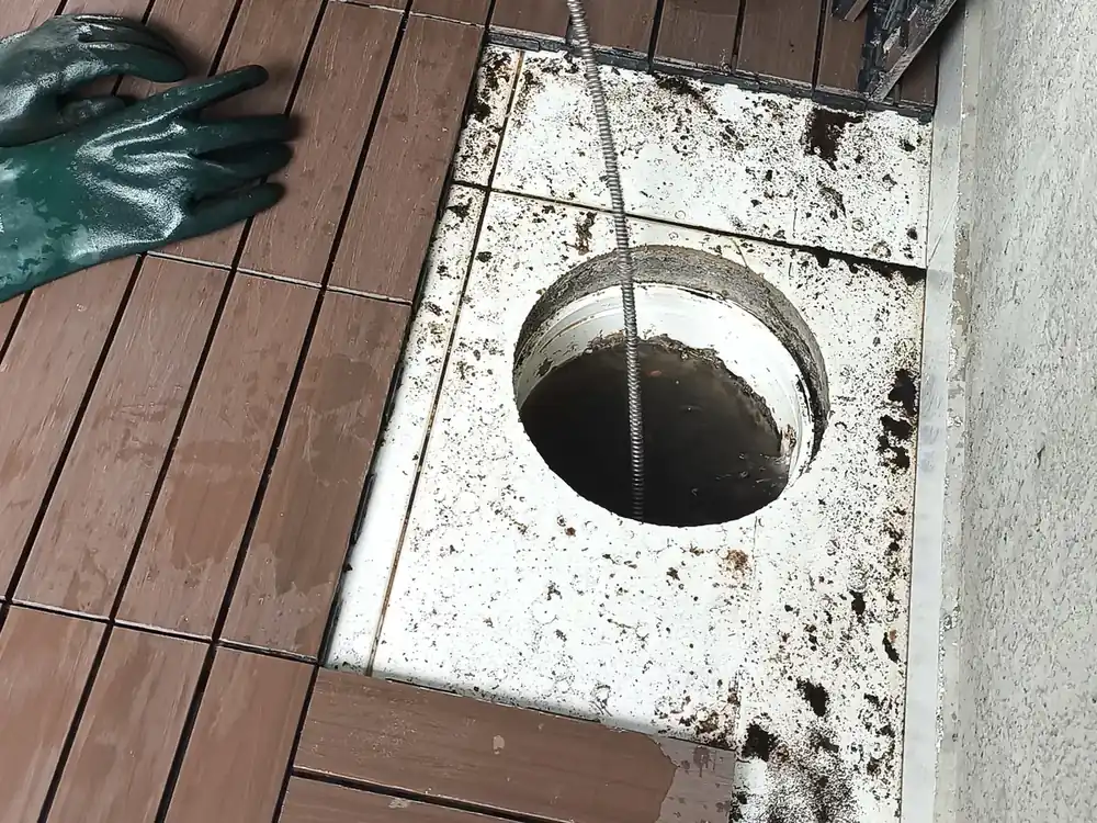 Ralo externo aberto em um deck de madeira durante o desentupimento
