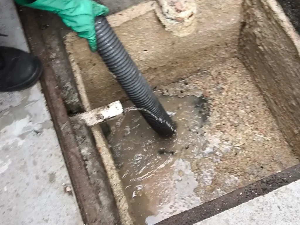 Mangueira de sucção retirando gordura de uma caixa de gordura retangular